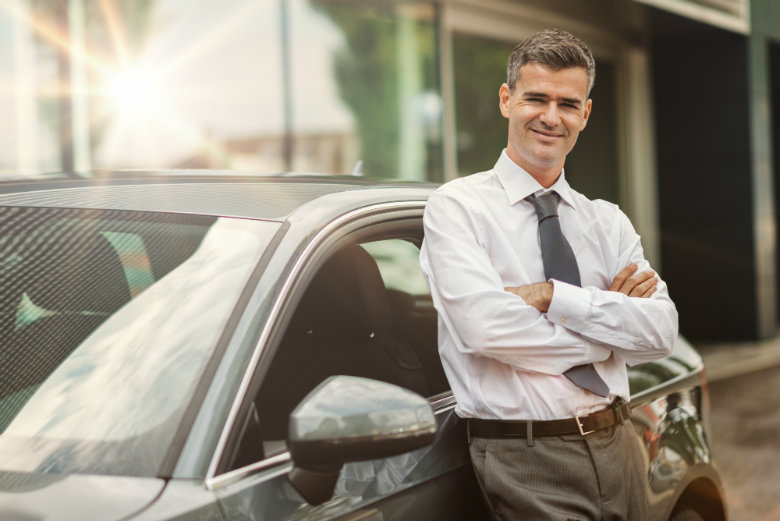 Business man leaning against car 