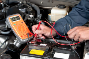 Auto mechanic checking car battert voltage