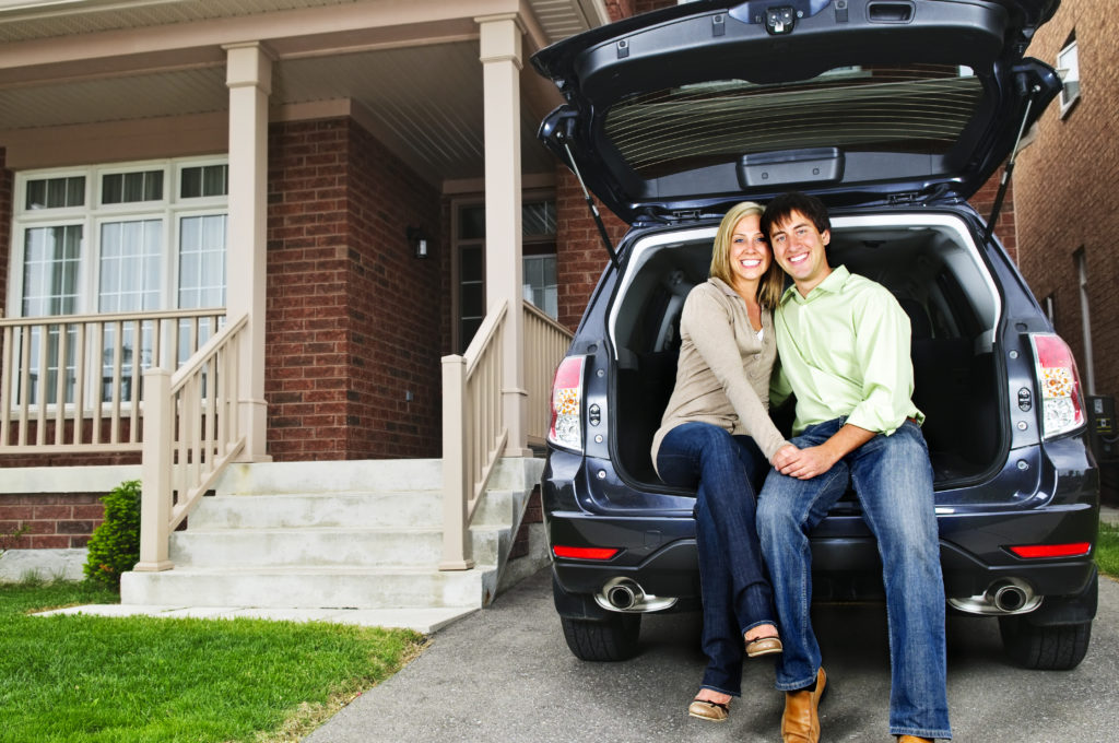 Couple sitting in back of car in driveway